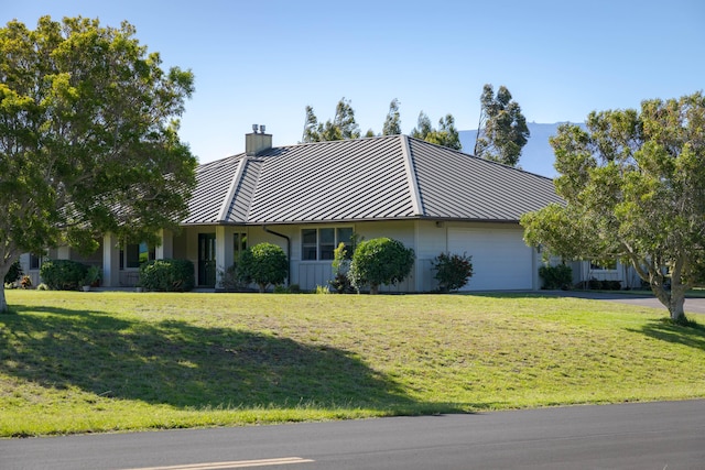 view of front facade featuring a chimney, a standing seam roof, metal roof, a garage, and a front lawn