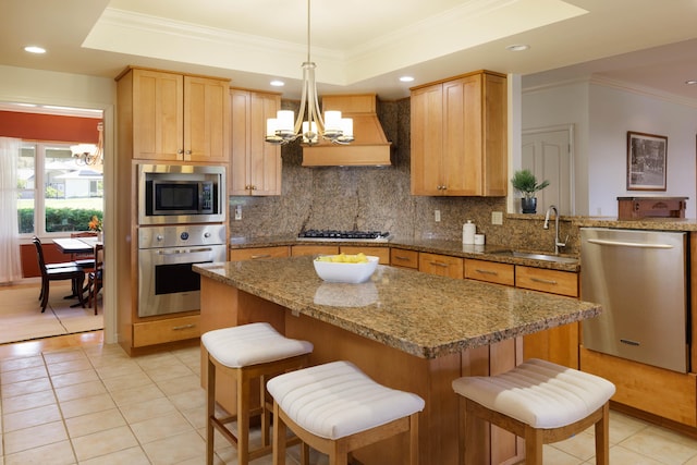 kitchen featuring appliances with stainless steel finishes, custom exhaust hood, a sink, and a notable chandelier