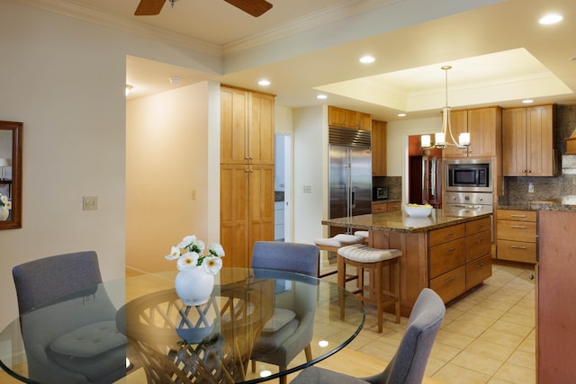 dining space with a ceiling fan, a tray ceiling, recessed lighting, light tile patterned flooring, and crown molding