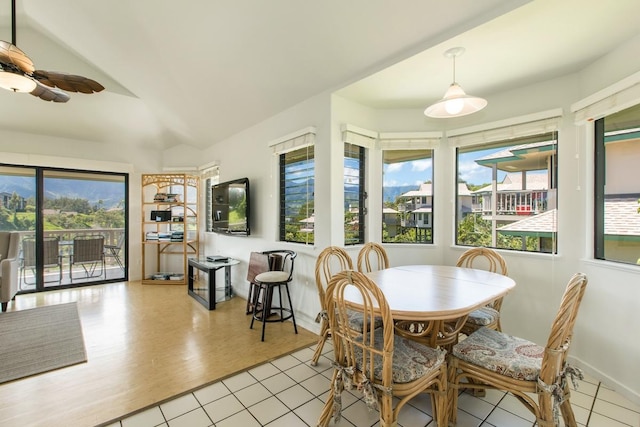 dining space with baseboards, wood finished floors, a ceiling fan, and vaulted ceiling