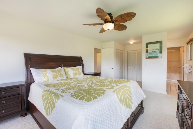 bedroom with light carpet, a ceiling fan, and multiple closets