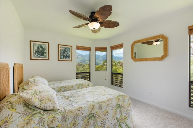 bedroom featuring access to outside, a mountain view, carpet, baseboards, and ceiling fan