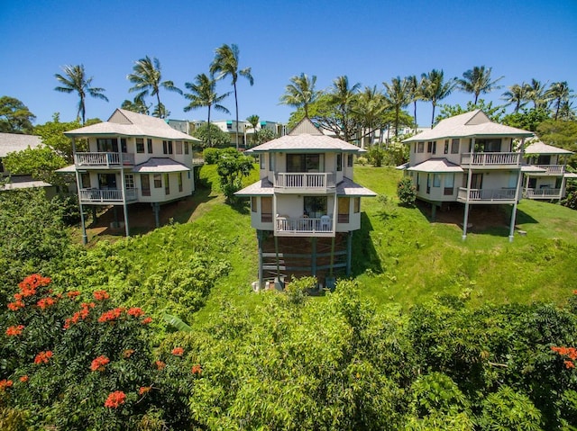 rear view of property featuring a lawn and a balcony