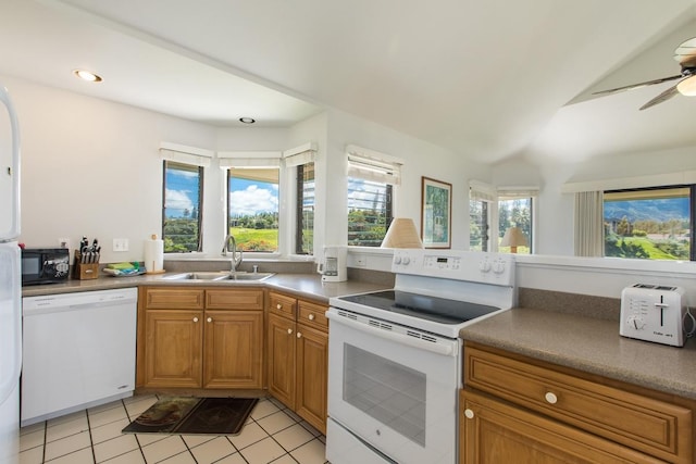 kitchen with brown cabinets, light tile patterned flooring, white appliances, a ceiling fan, and a sink