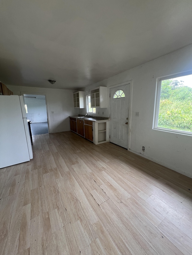 kitchen with a sink, baseboards, freestanding refrigerator, light wood-style floors, and open shelves