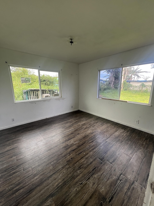 spare room featuring baseboards and dark wood-style flooring