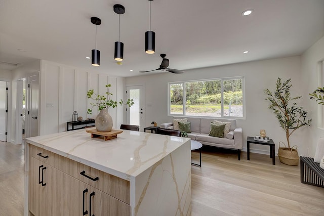 kitchen featuring light brown cabinetry, a kitchen island, light stone countertops, modern cabinets, and light wood-style floors