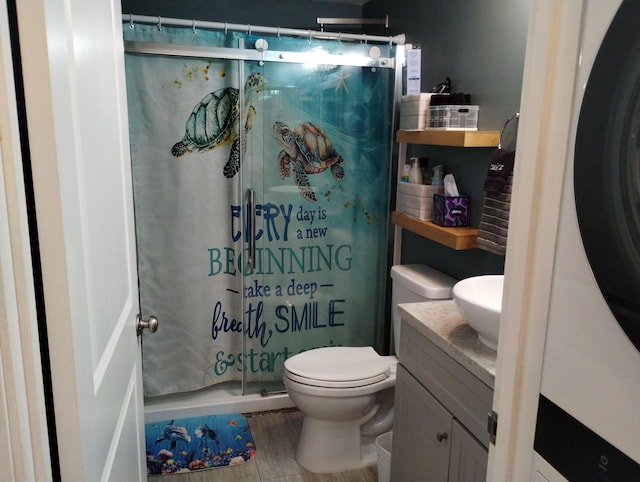 bathroom featuring a shower stall, toilet, wood finished floors, washer / clothes dryer, and vanity