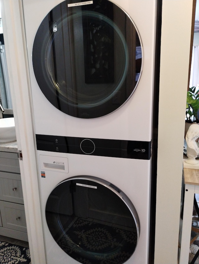 laundry area featuring laundry area, stacked washer and clothes dryer, and a sink