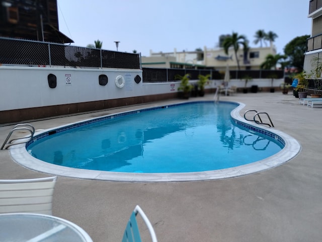 pool with a patio area and fence