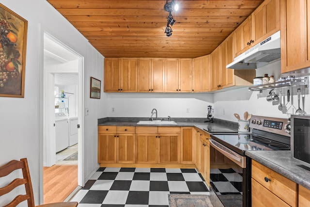 kitchen with dark floors, under cabinet range hood, electric range, independent washer and dryer, and a sink