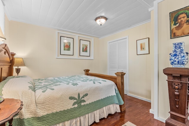 bedroom featuring a closet, wooden ceiling, crown molding, and wood finished floors