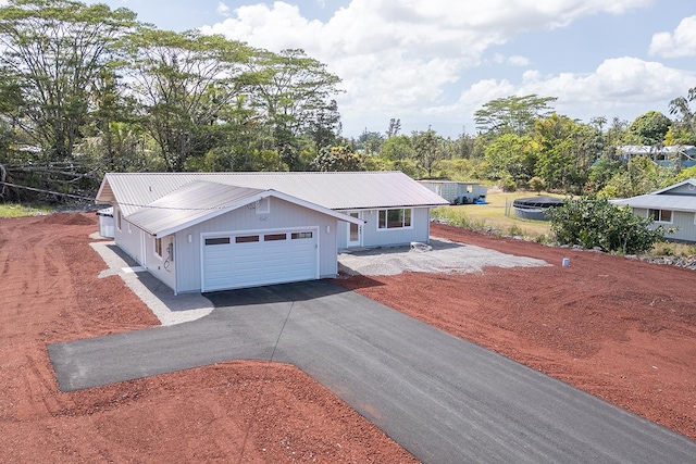 ranch-style home with aphalt driveway, a garage, and metal roof