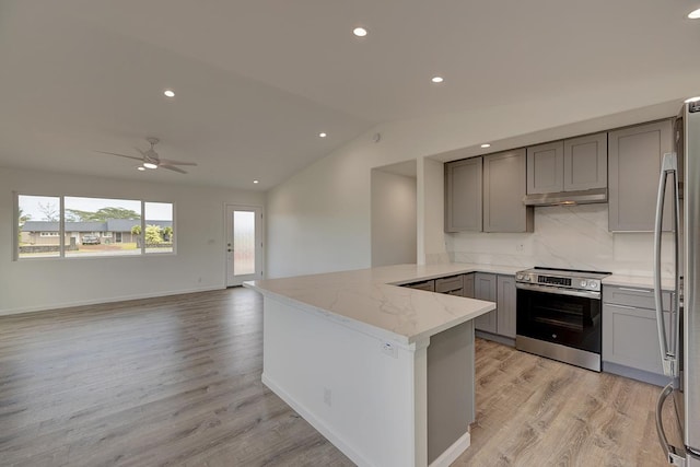 kitchen with vaulted ceiling, gray cabinets, appliances with stainless steel finishes, light wood-style flooring, and a peninsula