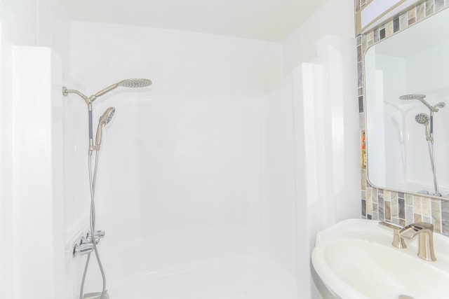 full bath featuring a sink, decorative backsplash, and a shower