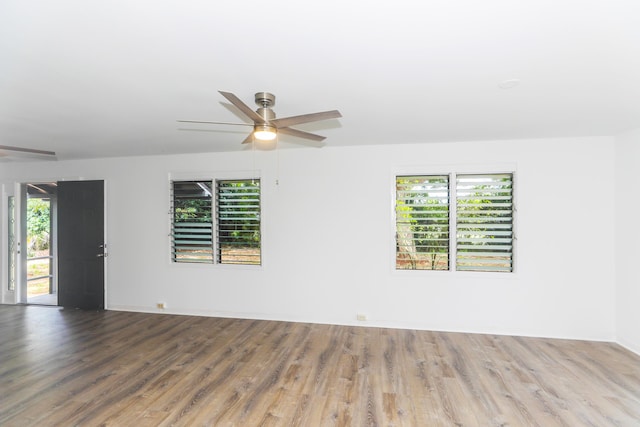 empty room featuring a ceiling fan, wood finished floors, and a healthy amount of sunlight