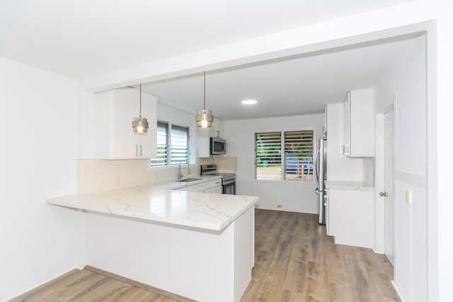 kitchen with light stone counters, light wood-style flooring, a sink, stainless steel appliances, and white cabinets