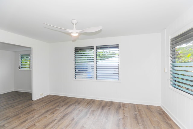 empty room featuring ceiling fan, wood finished floors, baseboards, and a healthy amount of sunlight