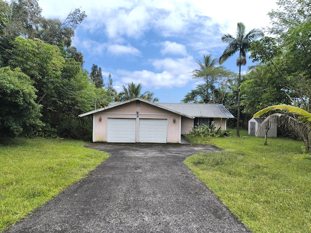 view of front of house with an outbuilding, an attached garage, a front yard, and driveway