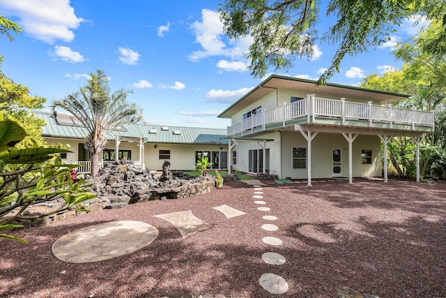 rear view of property with stucco siding and metal roof