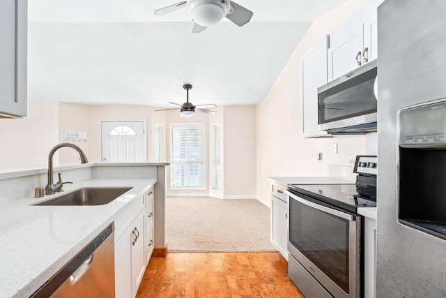 kitchen featuring a sink, white cabinetry, appliances with stainless steel finishes, baseboards, and ceiling fan