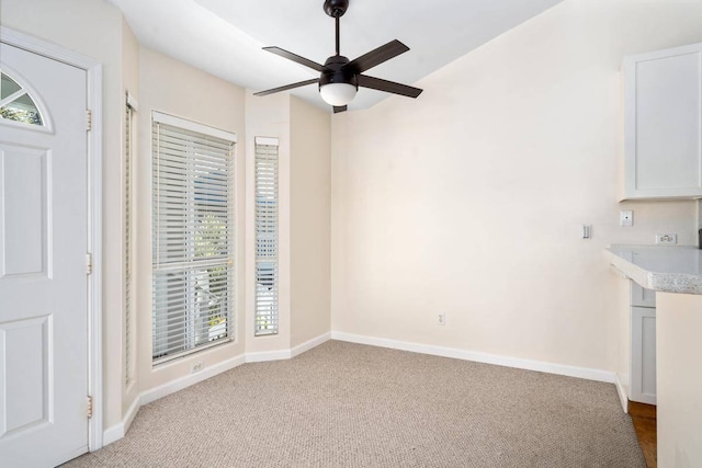 interior space with ceiling fan, light colored carpet, and baseboards