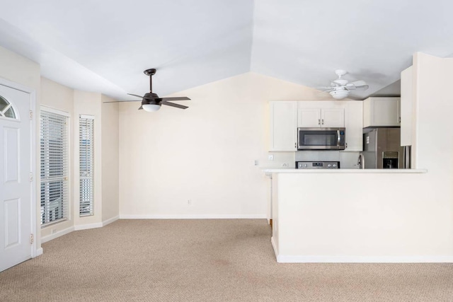 kitchen featuring light colored carpet, appliances with stainless steel finishes, a ceiling fan, and white cabinetry