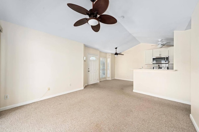 unfurnished living room with light colored carpet, baseboards, and lofted ceiling