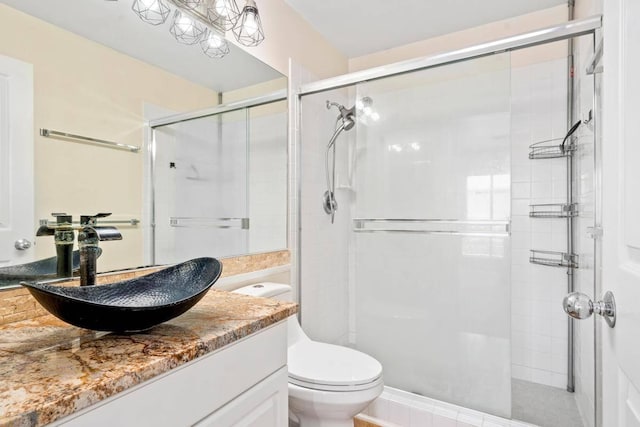 bathroom featuring toilet, a stall shower, and vanity