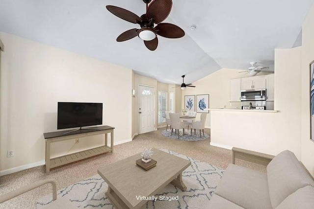 living room featuring lofted ceiling, light colored carpet, and baseboards