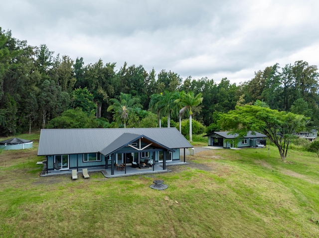 rear view of house featuring a lawn and metal roof