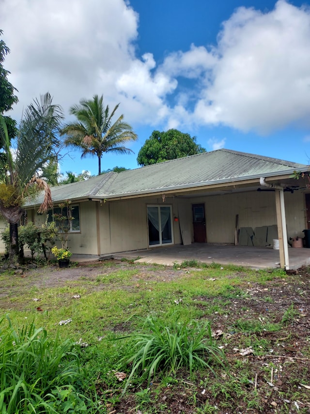 rear view of house featuring metal roof, a carport, and a patio area