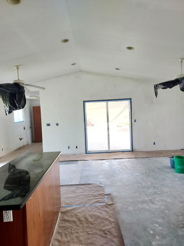 kitchen with vaulted ceiling, dark countertops, unfinished concrete flooring, and a ceiling fan