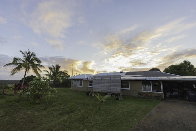 back of property at dusk featuring a carport, driveway, and a yard