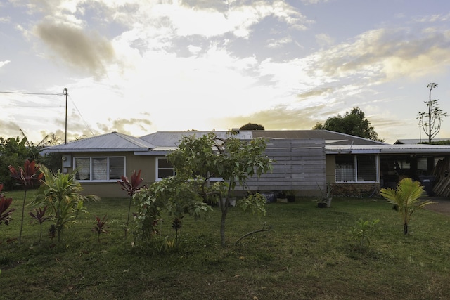 rear view of house with an attached carport, metal roof, and a yard