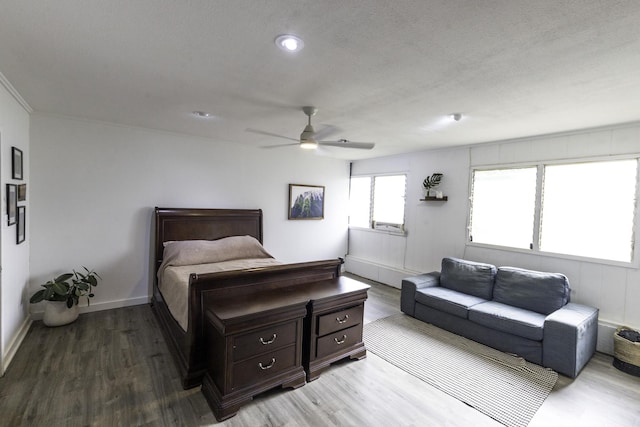 bedroom with a ceiling fan, wood finished floors, and baseboards