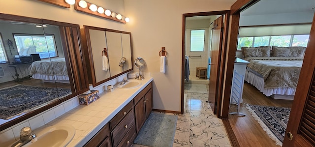 ensuite bathroom with a sink, a healthy amount of sunlight, marble finish floor, and connected bathroom