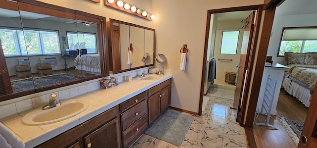 ensuite bathroom with marble finish floor, baseboards, connected bathroom, and a sink