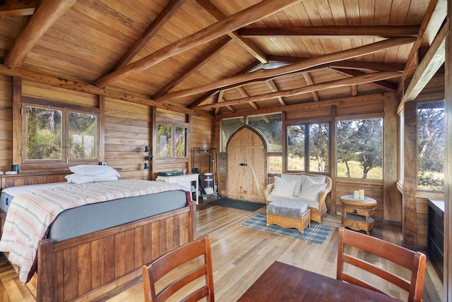 bedroom featuring lofted ceiling with beams, wooden walls, wood ceiling, and wood finished floors