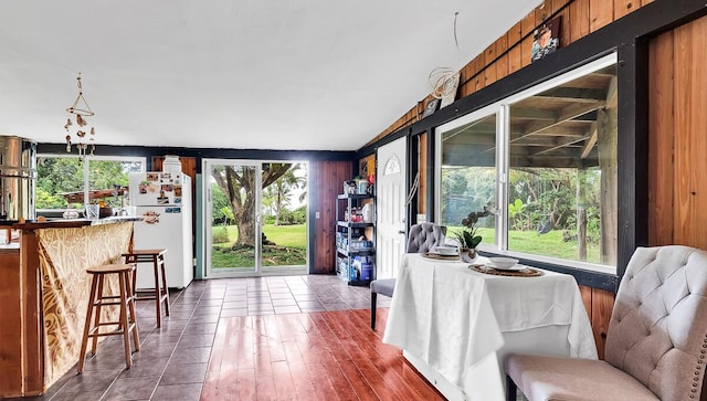 dining area featuring wood walls and dark tile patterned flooring