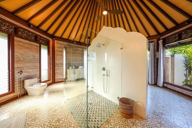 interior space featuring a shower stall, vaulted ceiling, and toilet