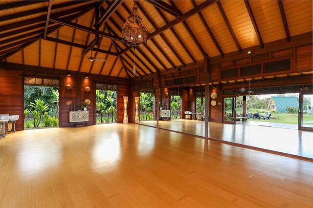interior space with a notable chandelier, wood finished floors, lofted ceiling, and a healthy amount of sunlight