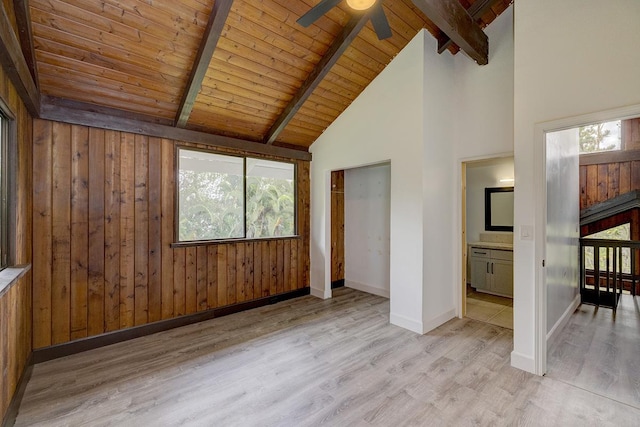 unfurnished bedroom with beamed ceiling, wood finished floors, baseboards, multiple windows, and wooden ceiling