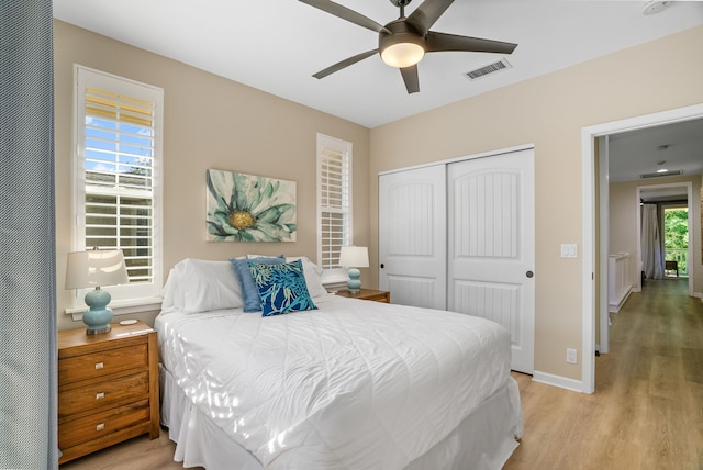 bedroom featuring a closet, visible vents, baseboards, a ceiling fan, and light wood-style floors