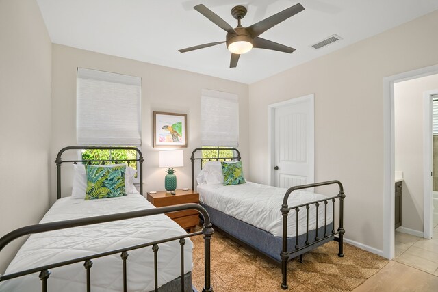 bedroom featuring baseboards, ensuite bathroom, visible vents, and a ceiling fan
