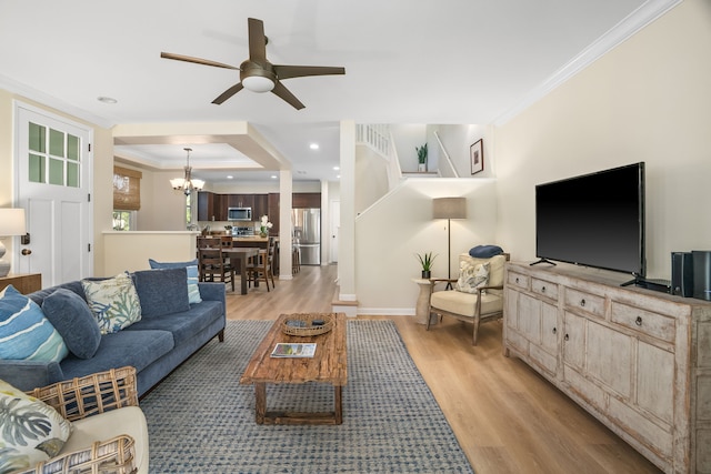 living room featuring ceiling fan with notable chandelier, light wood-type flooring, baseboards, and ornamental molding