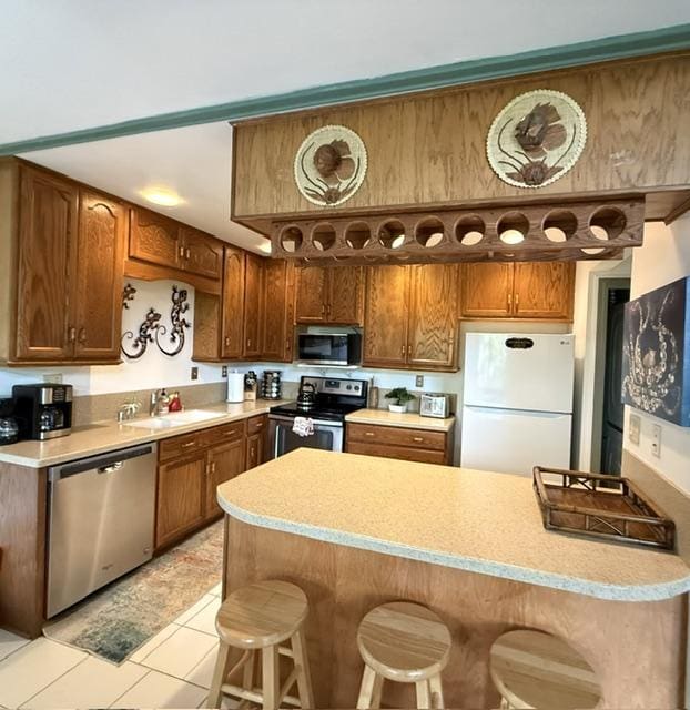 3880 Wyllie Rd Unit 8C, Princeville, HI 96722 - kitchen featuring appliances with stainless steel finishes, light countertops, a kitchen breakfast bar, and a sink