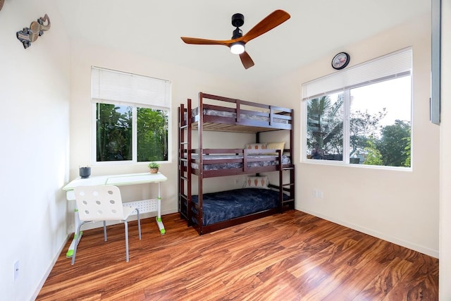 bedroom with baseboards, multiple windows, a ceiling fan, and wood finished floors
