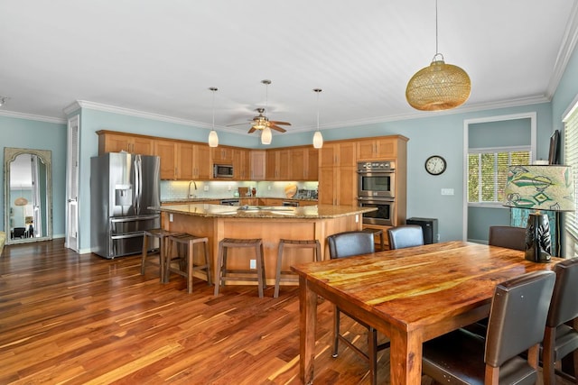 dining room featuring ornamental molding, dark wood-type flooring, and a ceiling fan
