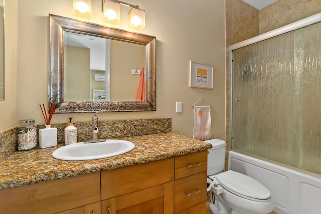bathroom featuring toilet, bath / shower combo with glass door, and vanity